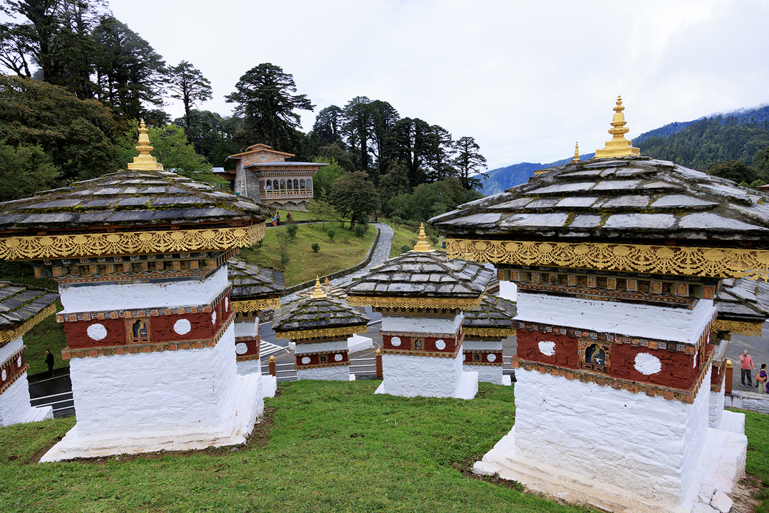 Bhutanese monastery and fluttering prayer flags against high Himalayan peaks